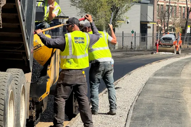 a group of men in reflective vests standing on a road